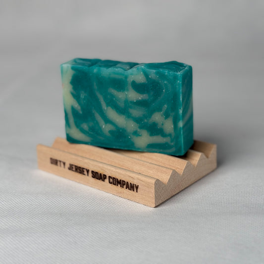 Green and white swirled soap bar on a wooden stand with 'Dirty Jersey Soap Company' branding.